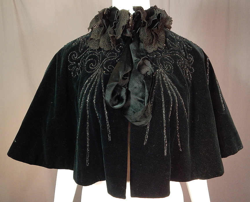 Victorian Midnight Blue Velvet Jet Beaded Lace Trim Cloak Cape Capelet
This antique Victorian era midnight blue velvet jet beaded lace trim cloak cape capelet dates from 1890. It is made of a dark midnight blue velvet fabric, with jet beading, black lace and ribbon trim edging the neckline.