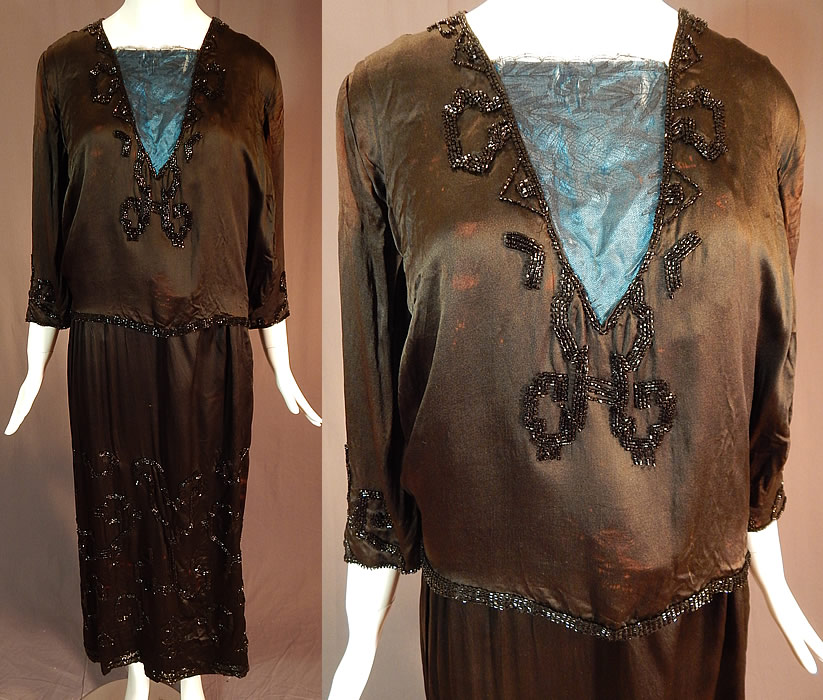 Vintage Art Deco Black Silk Pyramid Beaded Watteau Back Drape Flapper Dress
This fabulous flapper dress has a Grecian style, with layered tunic design, watteau back drape panel attached at the shoulders and bottom skirt hem, backed in a blue silk fabric, black Chantilly lace trim insert on the front top, layered sleeves attached underneath to a silk camisole lining inside, a beaded rope tassel ends sash belt, snaps closures along the side and shoulder. The dress measures 51 inches long, with a 38 inch bust, 30 inch waist, 42 inch hips, 14 inch back and 19 inch long sleeves.