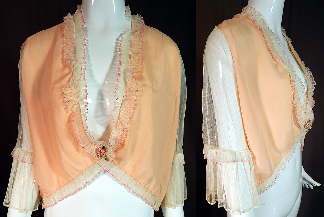 Vintage Pink Silk White Ruffle Rosette Trim Lingerie Boudoir Bed Jacket
This vintage pink silk white ruffle rosette trim lingerie boudoir bed jacket dates from the 1930s. It is made of a pastel pinkish peachy color silk fabric with sheer white net sleeves and pleated ruffle trim accented with pink crochet lace edging. There is a pastel silk ombre ribbon work trim on the front waist.