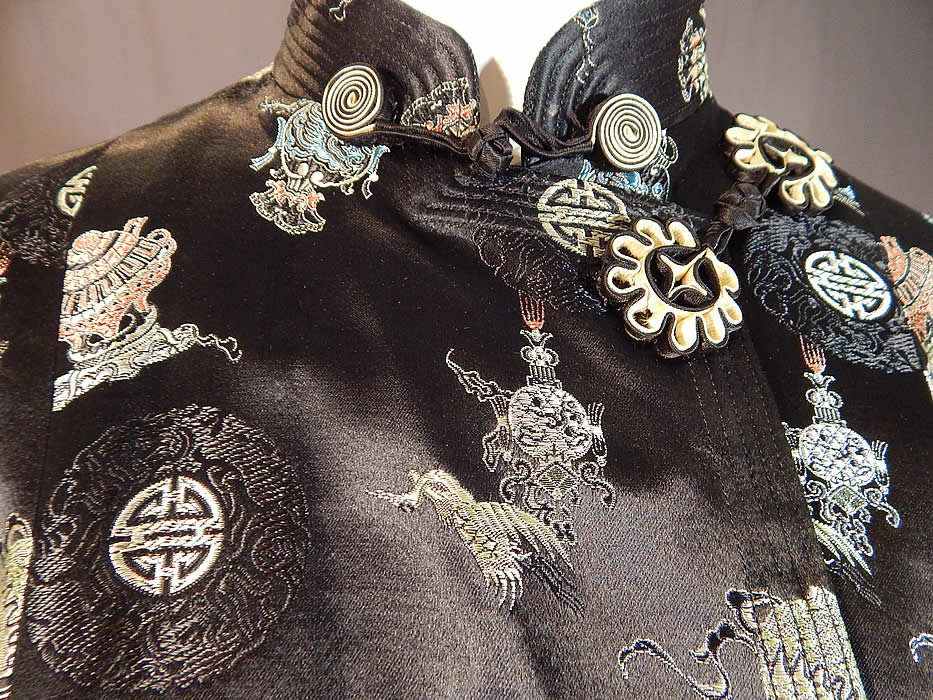 Vintage Hong Kong Chinese Character Ji Lucky Black Silk Damask Coat Jacket
This beautiful black Chinese inspired evening coat jacket has a loose fitting boxy style, is a short mid hip length, with long full sleeves, rolled cuffs, a mandarin collar, side slit pockets, black and white silk knotted button toggle loop closures and is fully lined with broad shoulder padding sewn inside. 