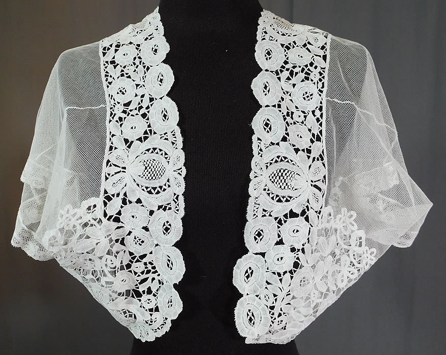 Edwardian White Net Duchesse Bobbin Tape Lace Bolero Jacket Shrug Top
This Edwardian era antique white net duchesse bobbin tape lace bolero jacket shrug top dates from 1910. It is made of a sheer white net with filmy linen half stitch, veined flowers and leaves, joined by braided plaits and Valenciennes lace trim cuffs edging