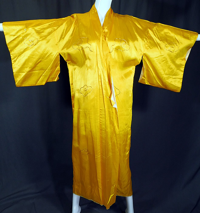 Vintage WWII Japanese Gold Couching Embroidery Dragon Yellow Kimono Robe
There are gold embroidered smoke clouds on the front, sleeves and a large dragon on the back looking down on Mount Fuji, a pagoda temple shrine and boat. This WWII souvenir Japanese dragon kimono robe has wide kimono sleeves, an open front with no closure and is fully lined in a white fabric.
