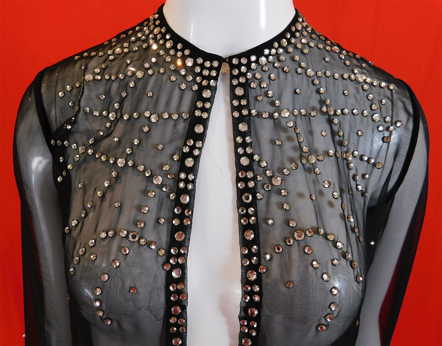 Vintage Art Deco Style Sheer Black Rhinestone Beaded Glitzy Evening Coat Jacket
This glamorous glitzy evening jacket has a long mid length loose fitting style, with an open front, hook closure at the neck, long full sleeves with snap closures at the cuffs and is sheer, unlined. 