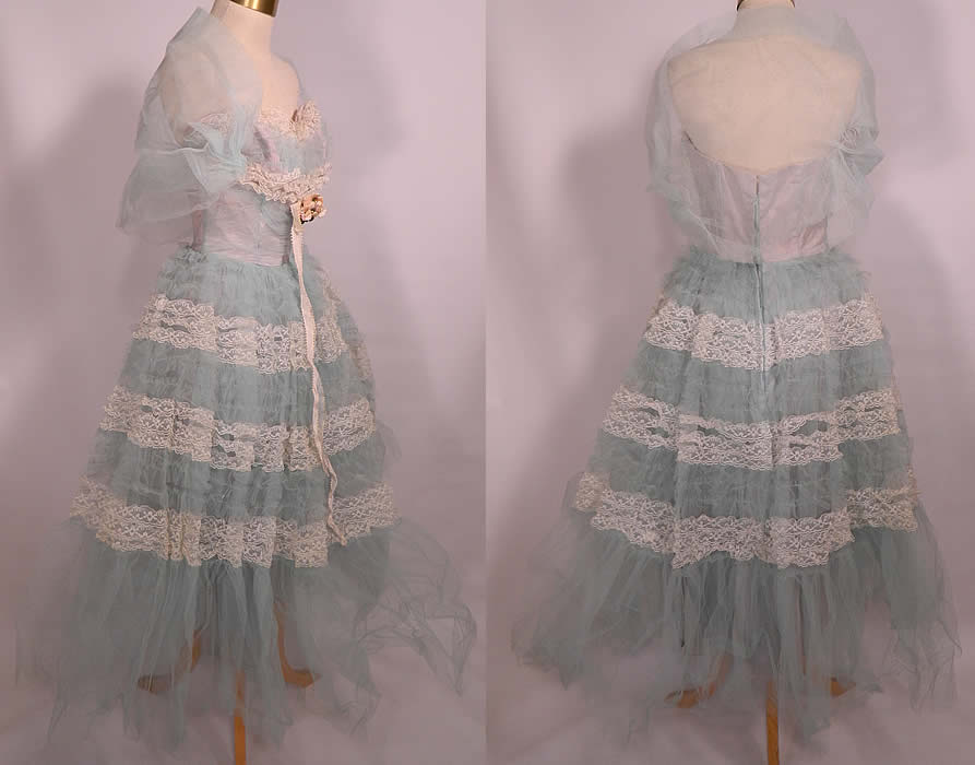 Vintage White Lace Blue Ruffle Tulle Net Strapless Formal Cupcake Dress & Shrug. There is a white silk ribbon and bow trim on the front with a peach flower rosette trim. This pretty girly cosplay cupcake style party prom dress formal is strapless, with a fitted bodice, sweetheart front neckline and voluminous very full layered poufy skirt. There are stays boning sewn inside the bodice lining and back zipper closure. The dress measures 38 inches long, with a 24 inch waist and 36 inch bust. 