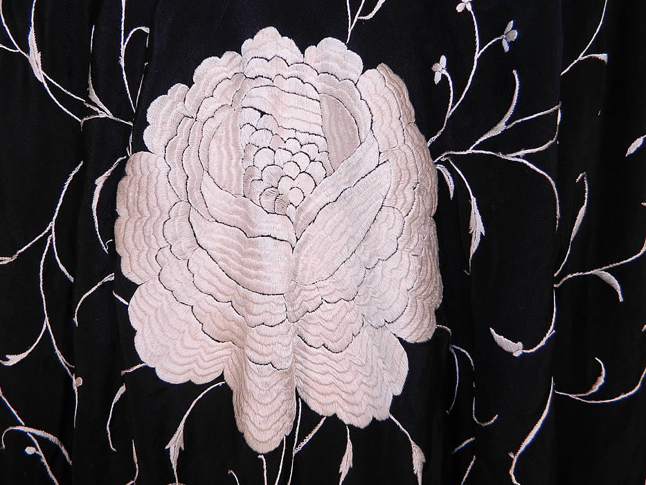 Antique Black & White Floral Silk Embroidered Canton Piano Shawl . There is a floral spiral vine leaf design, with four larger embroidered white roses in each corner. There is a fabulous hand knotted macram&eacute; black silk fringe which measures 20 inches long surrounding the entire shawl with rounded corners. 