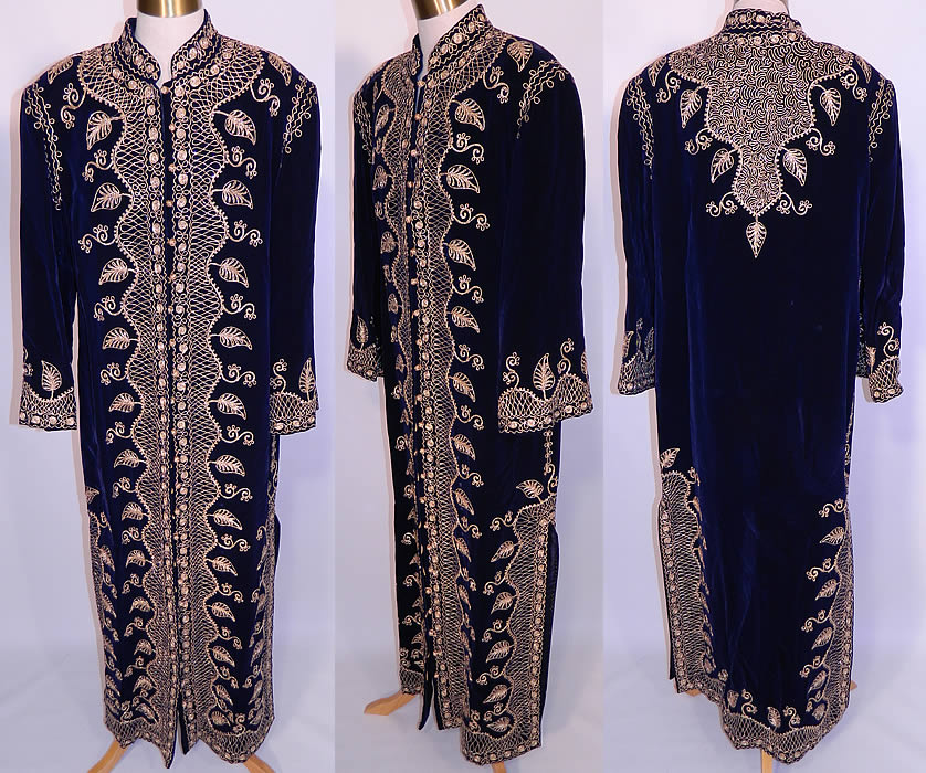 Vintage Adonis Lebanon Blue Velvet Gold Embroidered Boho Kaftan Robe Coat. It is made of a dark blue velvet fabric, with gold metallic braiding soutache embroidery work done in a decorative ethnic scrolling, spiral, vine leaf pattern design. This exquisite ethnic hippie chic, bohemian, loose fitting kaftan style robe coat is a long floor length, with long full sleeves, shoulder padding, side slits skirted bottom, fully lined and gold metallic knotted buttons with loop closures all the way down the front