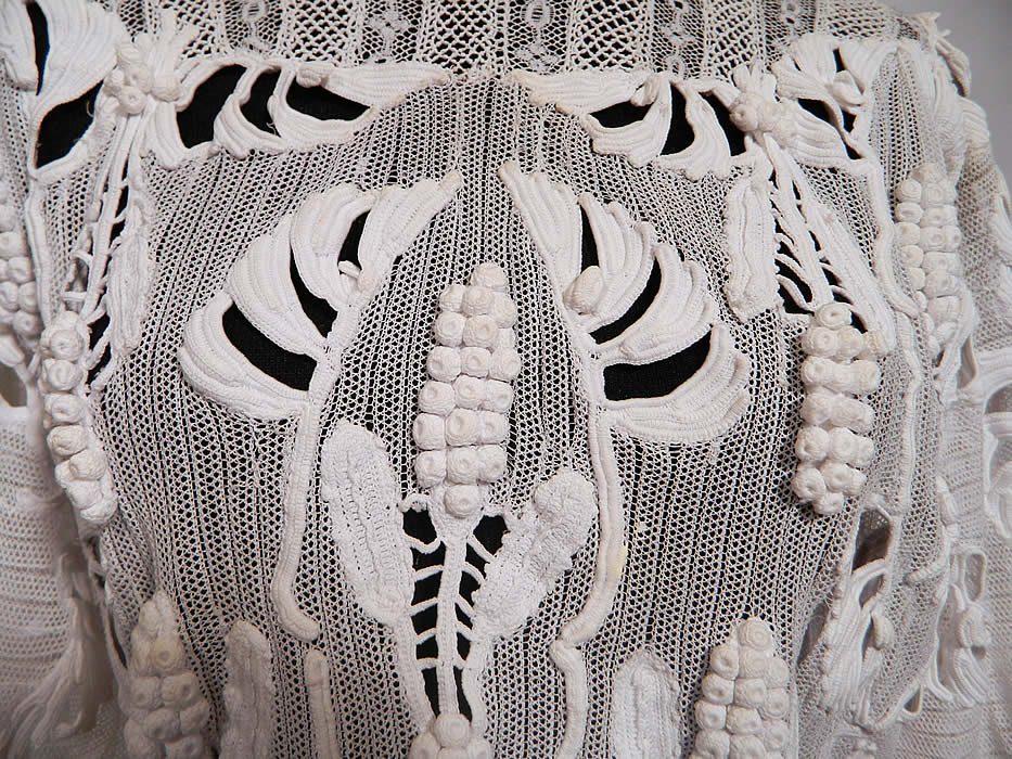 Edwardian White Net Irish Crochet Tape Lace Bodice Blouse. There is a patchwork of various styles of handmade laces and techniques. This lovely lace beautiful bodice blouse top has a fitted high neck layered lace scalloped collar, peplum skirted net bottom, long full tapered sleeves and pearl buttons down the back for closure. 