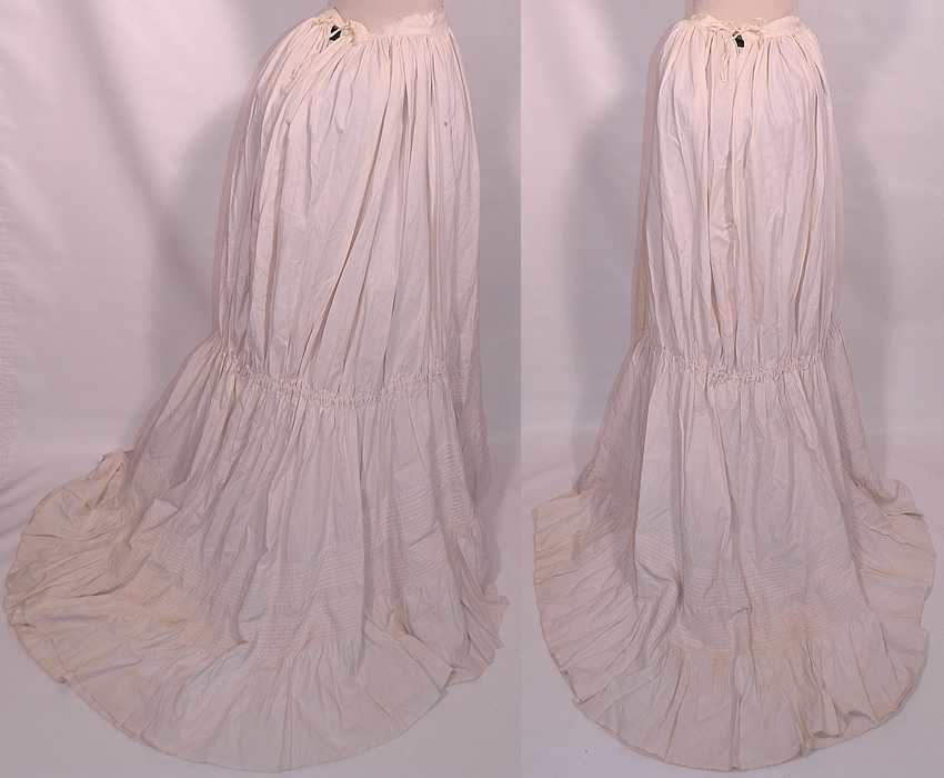 Victorian Pleated White Cotton  Bustle Back Train Bridal Wedding Petticoat Skirt. This beautiful bridal wedding petticoat skirt has a bustle back, with gathering on the back midway down, a long draping back train skirt, gathering on the waistband and an adjustable drawstring back closure. 