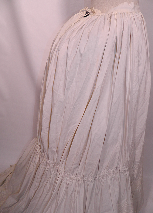 Victorian Pleated White Cotton  Bustle Back Train Bridal Wedding Petticoat Skirt. The petticoat measures 39 inches long in the front, 59 inches long in the back, with a 26 inch adjustable waist which can be made larger. It is in good condition, with only a few tiny pin holes. This is truly a rare and wonderful wedding bridal undergarment petticoat skirt!