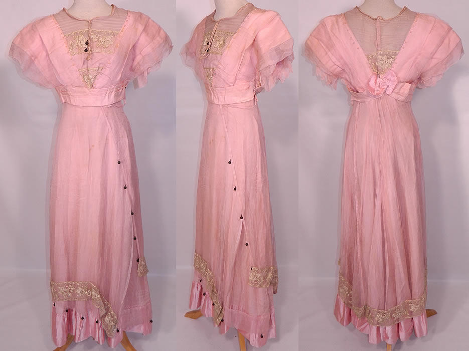 Edwardian Titanic Pink Silk Pearl Beaded Lace  Evening Gown Dress. This Edwardian Titanic era pink silk pearl beaded lace evening gown dress dates from 1912. It is made of a pastel pink silk fabric, with a sheer pink silk chiffon overlay, cream color embroidered net lace, pink pearl, black silk ball trim accents.