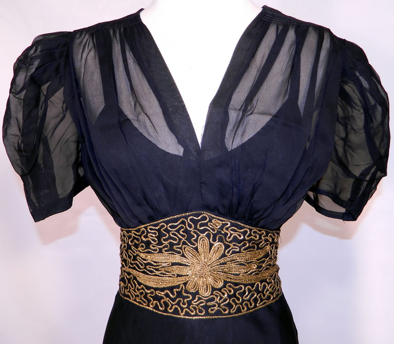 Vintage Black Silk Chiffon Gold Lam&eacute; Soutache Belted Evening Gown Dress & Slip. This gorgeous gown has a long floor length skirt, is sheer, unlined, with short puffy sleeves, smocking along the shoulders, a V front neckline, an attached cummerbund sash belt with button back and side zipper closure.