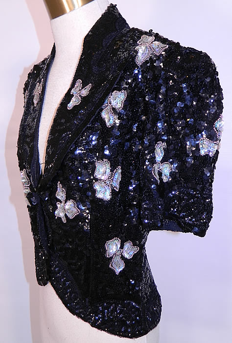 Vintage Black Net   Sequin Beaded Iridescent Gold Flowers Evening Jacket. It is made of a sheer black net fabric, completely covered with black sequins and an iridescent, gold beaded outlined flower pattern design. 