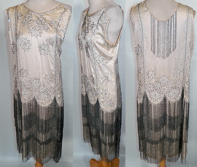 Vintage White Silk Rhinestone Silver Beaded Fringe Flapper Drop Waist Dress. This vintage Art Deco white silk rhinestone silver beaded fringe flapper drop waist dress dates from the 1920s. It is made of an off white ivory color silk satin fabric, with rhinestones and silver beading done in a floral starburst design. 