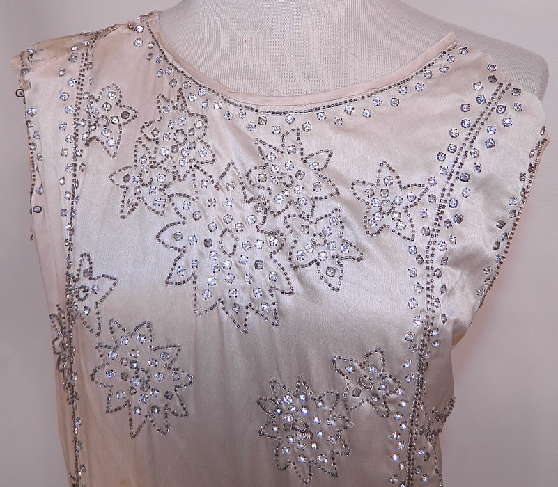 Vintage White Silk Rhinestone Silver Beaded Fringe Flapper Drop Waist Dress. This fabulous flapper dress has a loose fitting drop waist style, sleeveless, with a scalloped layered fringe skirt and fringe trim back. The dress measures 44 inches long, with 40 inch hips, a 40 inch waist, 40 inch bust and 21 inch long sleeves.