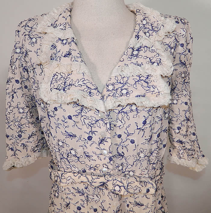 Vintage White Cotton Lace Blue Embroidered Stitching Belted Swing Day Dress. It is made of a white cotton fabric, with blue & white raised stitching soutache embroidery work done in a floral vine leaf design and white lace trim edging the collar and cuffs.