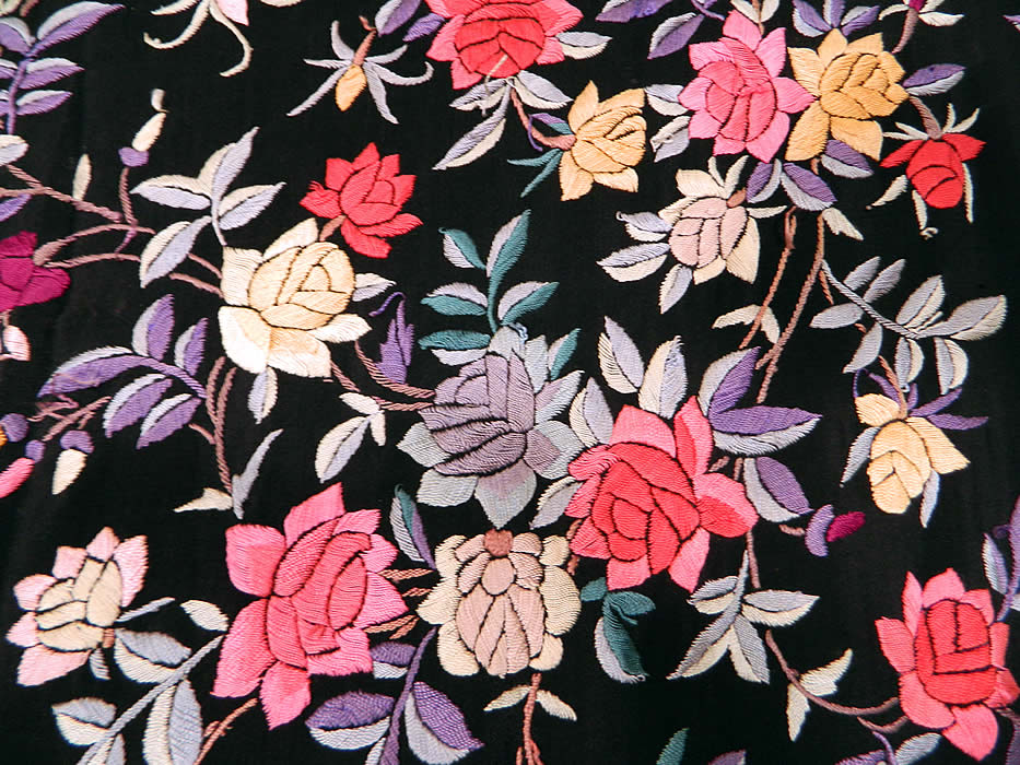 Antique Black Silk Floral Roses Pastel Embroidered Canton Piano Shawl. There is a lush floral foliage vine leaf pattern with a variety of rose flowers embroidered throughout. There is a fabulous hand knotted macramé black silk fringe which measures 18 inches long surrounding the entire shawl with rounded corners.