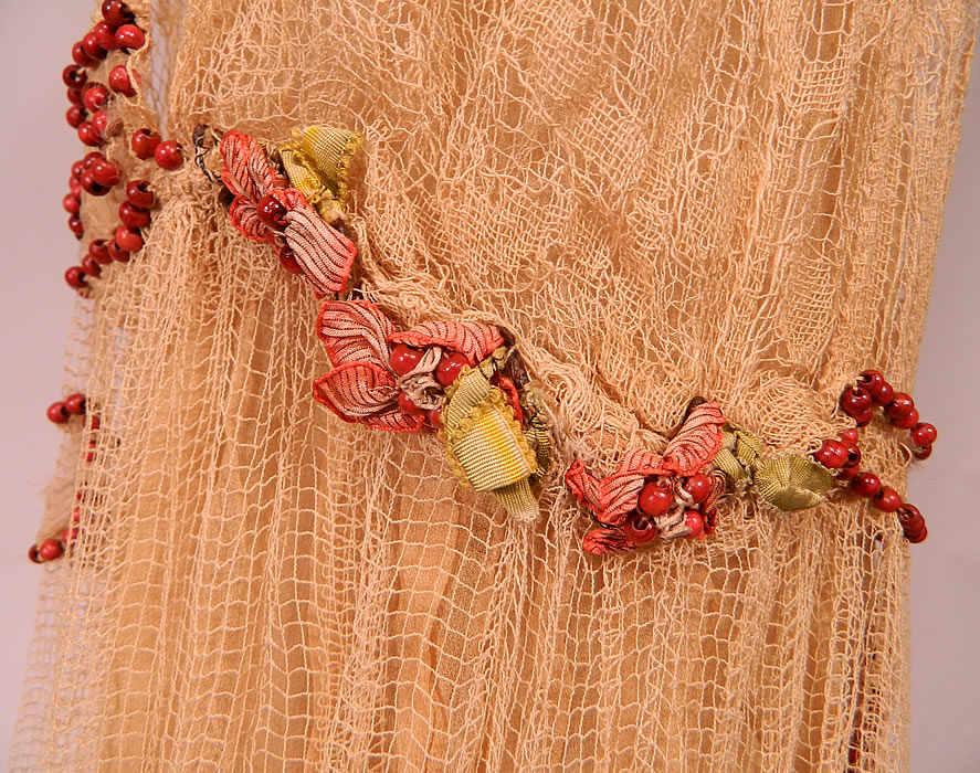 Vintage Cream Crochet Filet Lace Wood Beaded Rosette Drop Waist Flapper Dress
This lovely lace fabulous flapper dress has a layered, loose fitting, drop waist style, with short cap sleeves, pastel silk ombre ribbon work rosettes with wood beaded center trim along the side waist and is fully lined in a cream color sheer silk chiffon slip lining inside.