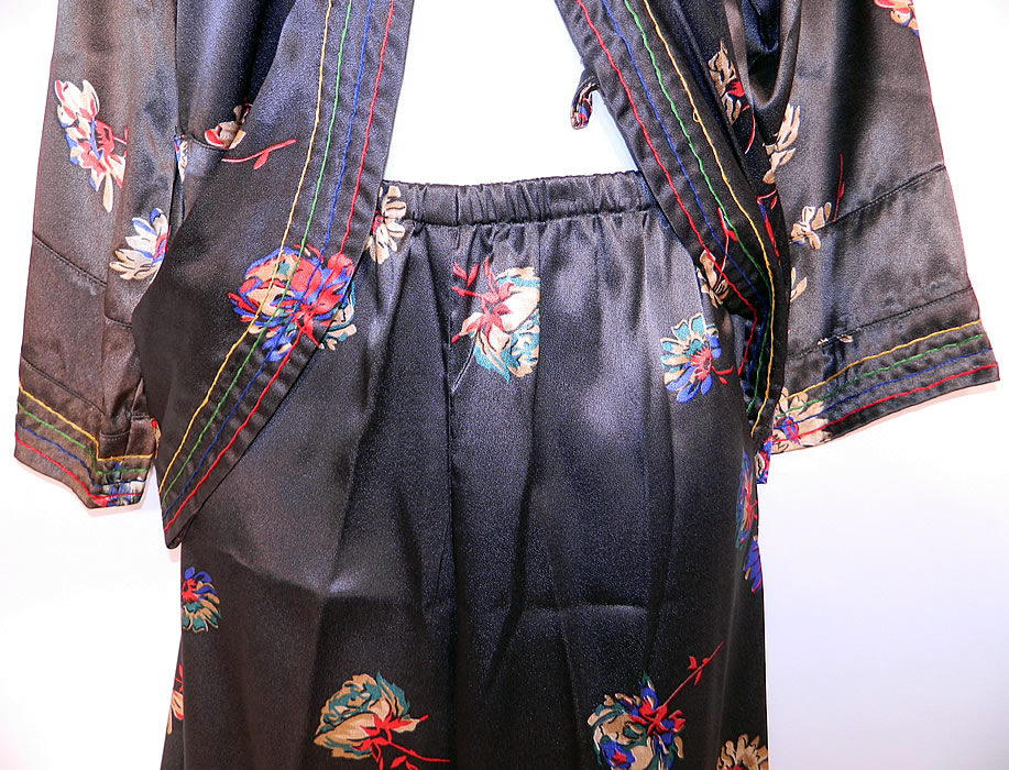 Vintage Black Silk Satin Flower Print Pajamas Robe Jacket Pants Lounge Set
This pretty two piece pajamas lounging set has a mid length short robe style jacket top, with rainbow pin striped trim edging, a fold over front snap closure, long full sleeves and is unlined. 