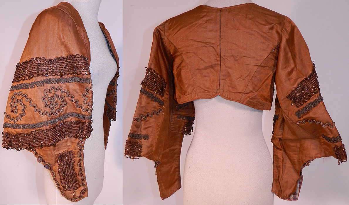 Victorian Civil War Brown Silk Bronze Beaded Bodice Bolero Cropped Spencer Jacket
This beautiful bodice bolero jacket short cropped spencer style top, has an open front with no closure, long flared pagoda style sleeves with fitted cuffs, steel cut button trim accents and is fully lined in a brown plaid check pattern lining inside. 