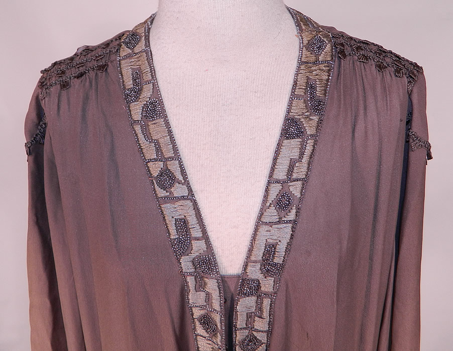 Vintage Art Deco Gray Silk Embroidered Silver Beaded Flapper Drop Waist Dress
This fabulous flapper dress has a loose fitting drop waist style, with ruched smocking along the shoulders, long full sleeves with gauntlet cut work open slit cuffs, overlapping skirt panels, a V front neckline, with hook closures down the front and is lined. 