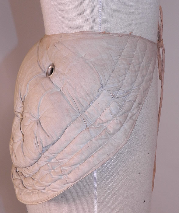 Victorian Antique Grommet Bustle Quilted Cotton Pad Pillow Crescent Crinolette
There is a linen cloth strap waistband belt with adjustable tie front closure. This unique undergarment would have been worn under a bustle skirt dress to expand the fullness or support the back drape of the fanned train skirt.
