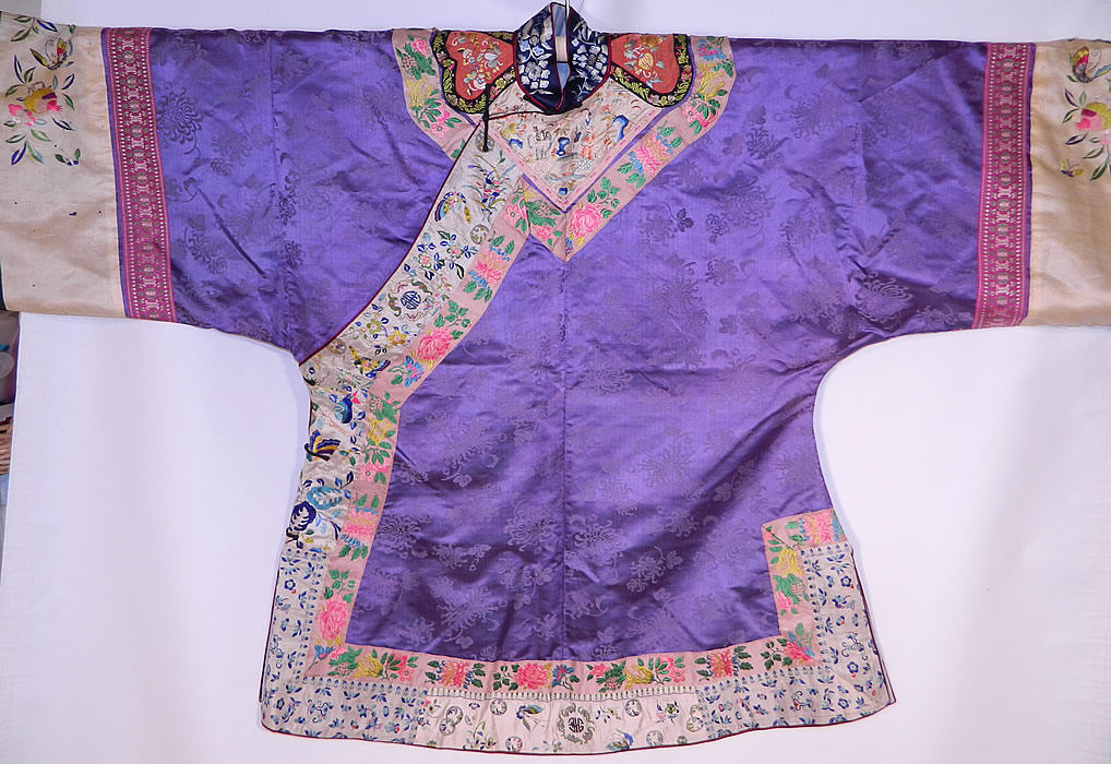 Antique Chinese Purple Silk Damask Floral Brocade Figural Embroidered Trim Robe
This magnificent Manchu womens robe has a blue silk embroidered mandarin collar, cinnabar color embroidered shoulder epaulettes, black silk knotted loop toggles for closure along the side, long full sleeves with wide cuffs, side skirt vents and has been fully relined in a blue silk fabric. 