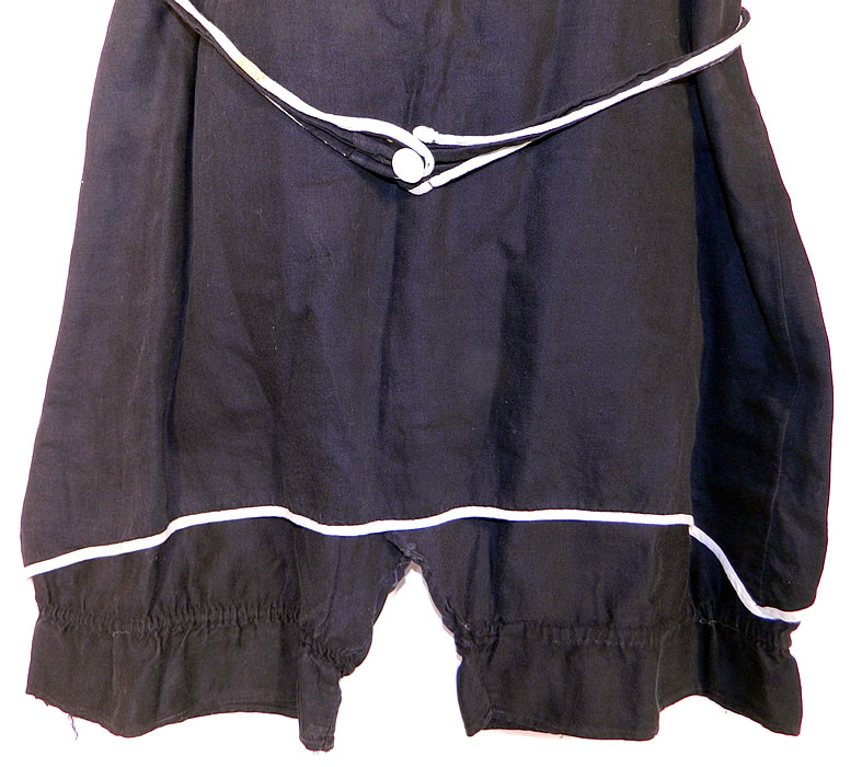 Vintage Black & White Cotton Belted Bathing Suit Swimsuit Dress & Bloomers
This fabulous flapper ladies bathing suit costume one piece swimsuit has a sleeveless style short tunic dress overlay with mother of pearl button closures on the shoulders, an attached belted tie sash with button front closure and short bloomer pantaloons pants sewn underneath, with gathered leg cuffs. 