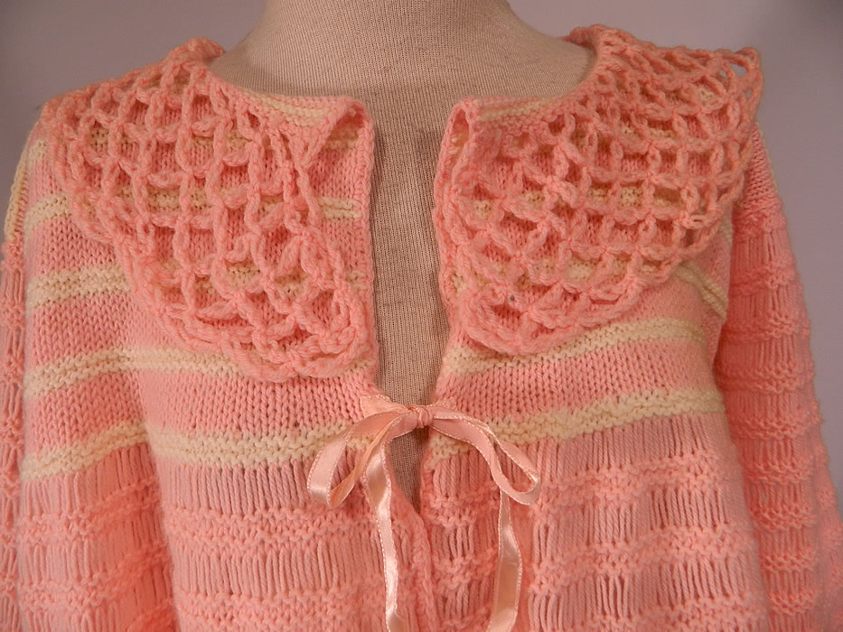 Vintage Hand Fashioned Ann Best Pink & White Knit Crochet Sweater Bed Jacket Top
This beautiful bed jacket style sweater top is loose fitting, with a flared bottom, large open lattice weave fold over round collar, long full sleeves with gathered scalloped cuffs, a pink silk ribbon tie front closure and is sheer, completely unlined. 