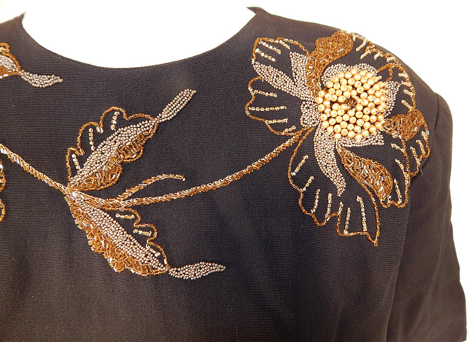 Vintage Eisenberg Originals Black Silk Crepe Gold Flower Beaded Cocktail Dress
This beautiful beaded cocktail dress has broad shoulder padding, short sleeves, a fitted waist with side tie belted sash, a long mid length skirt and back zipper closure. 