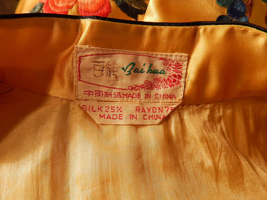 Vintage Bai hua Chinese Yellow Silk Rayon Embroidered Peony Flower Robe Coat
This stunning short surcoat style robe jacket is a mid length, with a mandarin collar, long full flared wide sleeves, with white silk colorful embroidered cuffs, trim edging, black button toggle trim closures down the front and is fully lined, with a "Bia hua Made in China" label sewn inside.