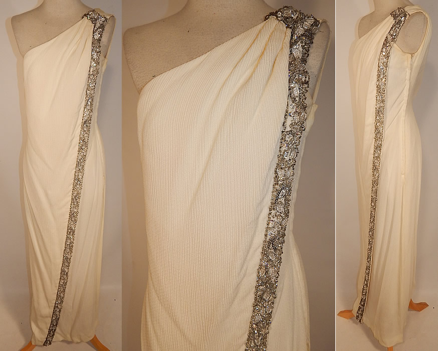 Vintage White Silk de Chine Silver Beaded One Shoulder Grecian Goddess Gown
This vintage white silk de chine silver beaded one shoulder Grecian goddess gown dates from the 1960s. It is made of an off white ivory color silk de chine fabric with a ribbed texture and silver, sequins, crystal bauble beaded trim along the side.