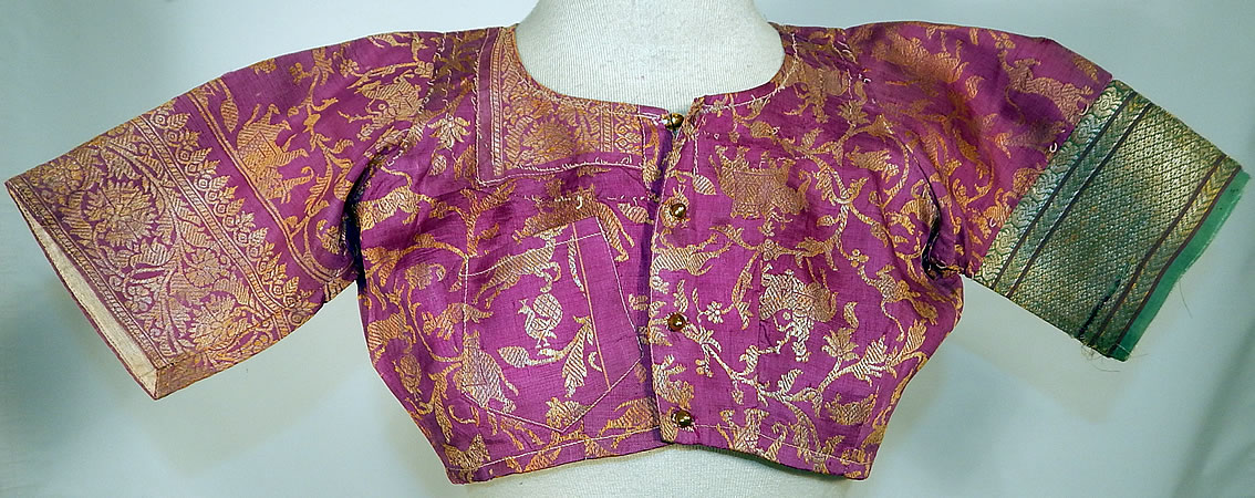 Vintage 19th Century Indian Purple Silk Sari Gold Lam&eacute; Lame Choli Crop Top Blouse
It is made a purple and gold lam&eacute; silk sari fabric with a woven floral fauna design of animals, tigers, deer, peacocks and hunters riding horses and elephants. 