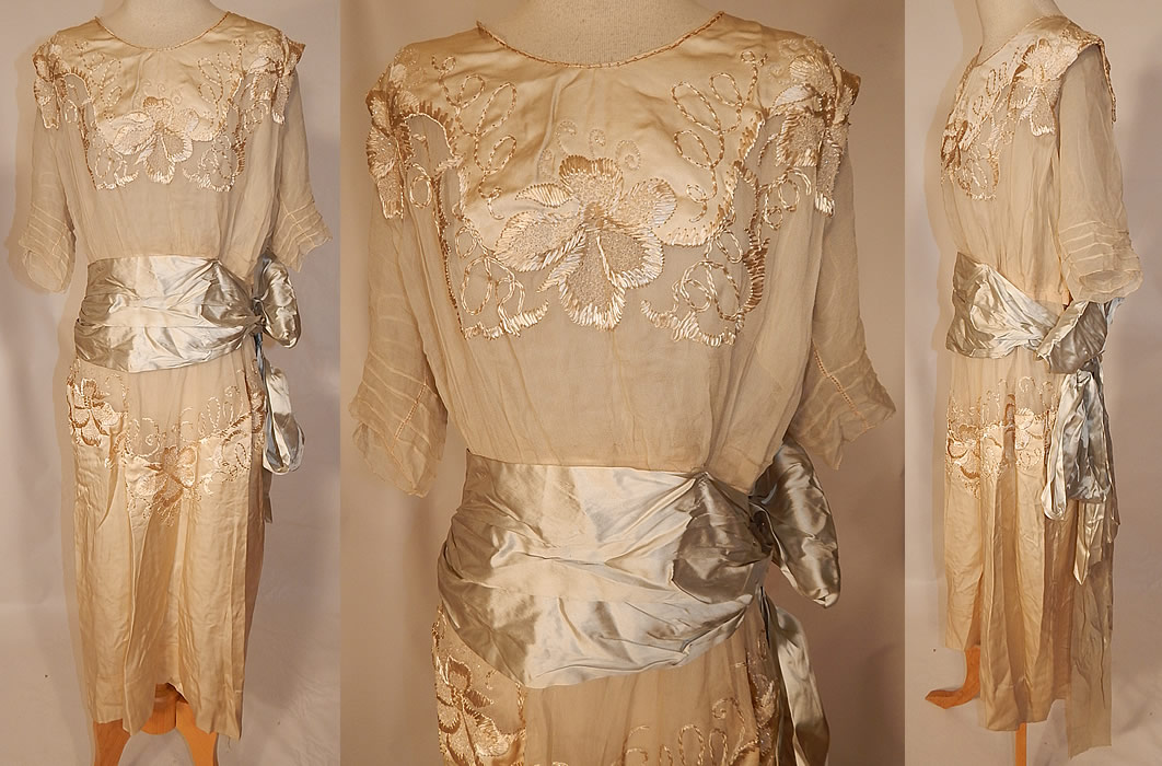 Edwardian Silk Embroidered Beaded Blue Ribbon Sash Belted Wedding Dress
This antique Edwardian era silk embroidered beaded blue ribbon sash belted wedding dress dates from 1915. It is made of an off white cream color silk satin and sheer silk chiffon fabric, with raised padded satin stitch hand embroidery work and beading done in a floral vine leaf pattern design.