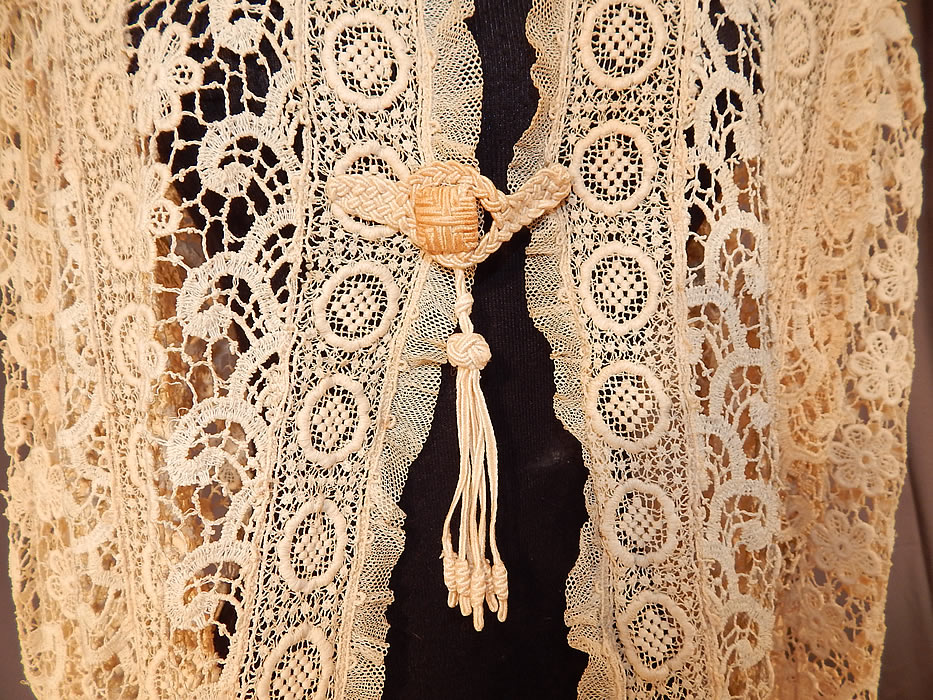 Vintage Edwardian Antique Cream Lace Cutaway Front Tailored Tail Coat Jacket
This lovely lace tail coat jacket is a long mid length, with a cutaway front, tailored back, long full tapered sleeves with flared lace cuffs, ruffled scalloped edge trim, a large crochet button toggle tassel closure at the waist and is sheer, unlined. 