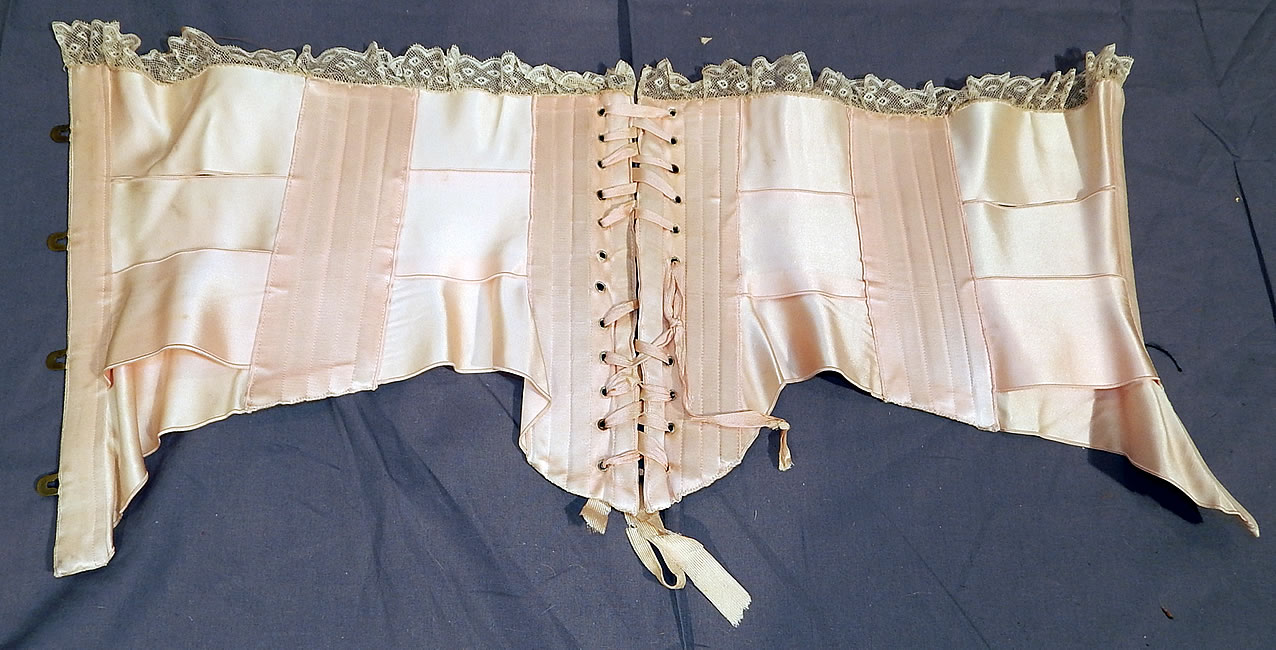 Victorian Antique Lace Trim Pink Silk Ribbon Short Negligee Night Corset Waist Cincher
The corset measures 11 inches long in the front, 9 1/2 inches long in the back, 7 1/2 inches long on the sides, with a 23 inch waist which is adjustable. It is in good condition, with only some fraying of the original silk corset strings lacing. This is truly a rare and wonderful piece of wearable antique corsetry lingerie art!