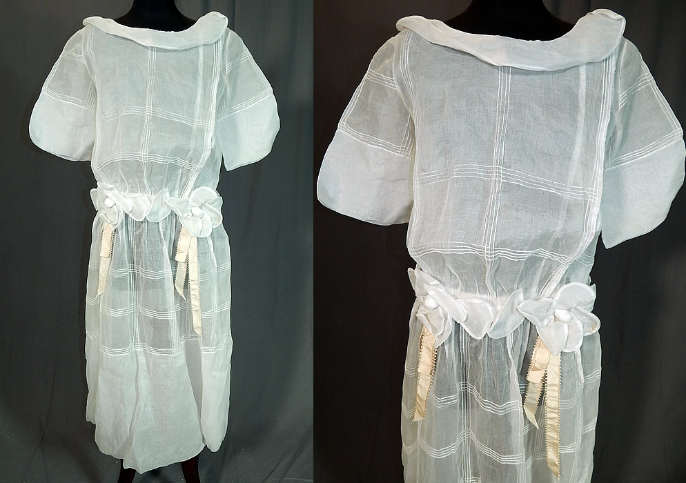 Vintage Windowpane White Organdy Rosette Ribbon Trim Drop Waist Dress
This vintage windowpane white organdy rosette ribbon trim drop waist dress dates from the 1920s. It is made of a sheer white windowpane organdy fabric, with rosette flower and cream silk ribbon trim around the waist.
