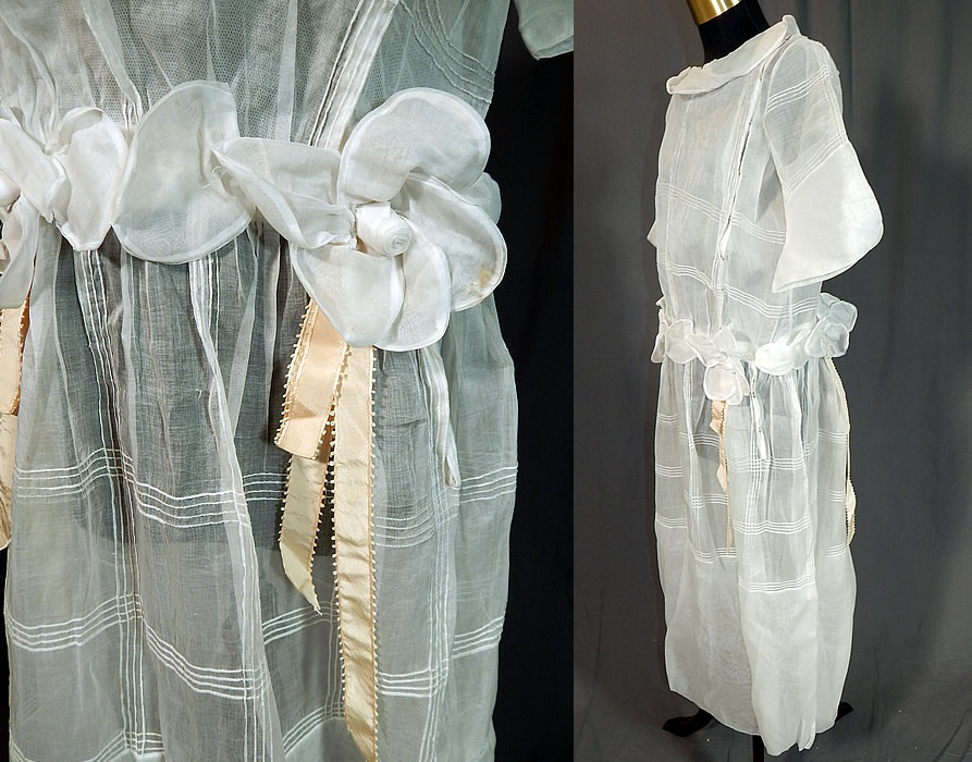 Vintage Windowpane White Organdy Rosette Ribbon Trim Drop Waist Dress
This pretty party dress has a drop waist, with a wide round Bertha style collar, full short sleeves, a rosette, ribbon trim attached belted waist, front top side snap closures and is sheer, lined only in the top with a cotton mesh net camisole.