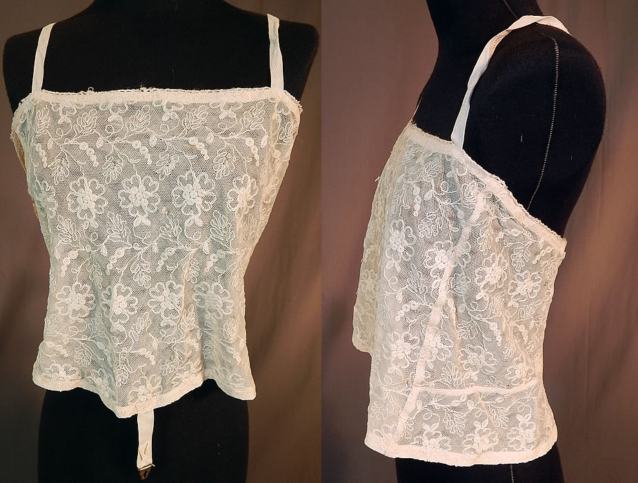 Vintage Edwardian Tambour Embroidery Net Lace Camisole Bra Bandeau Top
This vintage Edwardian era tambour embroidery net lace camisole bra bandeau top dates from 1915. It is made of an off white pale blush pink color net with tambour embroidery work lace done in a floral vine leaf design. This beautiful brassiere bra bandeau top has a short cropped camisole style, with cotton damask shoulder straps, hook closures down the back, a bottom front hook strap for attaching to garter stockings and is lined in net inside.