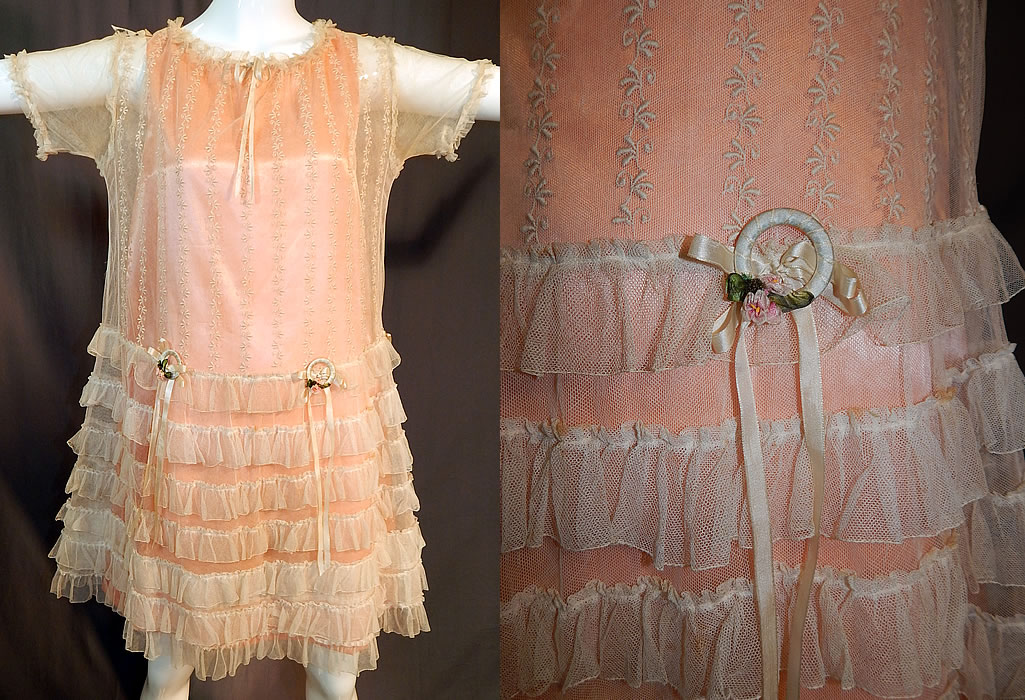 Vintage Embroidered Cream Net Lace Silk Ribbon Rosette Trim Peach Slip Dress
This vintage cream embroidered net lace silk ribbon rosette trim peach slip dress dates from the 1920s. It is made of an off white cream color sheer net fabric with embroidered floral vines on the top and cream silk ribbon bows and rosette ribbonwork garland wreath trim on the front waist.