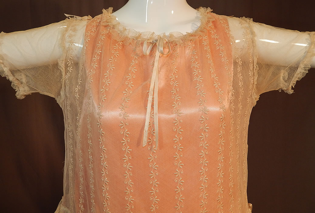 Vintage Embroidered Cream Net Lace Silk Ribbon Rosette Trim Peach Slip Dress
This lovely lace pretty party dress has a loose fitting drop waist style, with peach silk satin slip lining sewn inside, a ruffled ribbon drawstring neckline, short sleeves, a short skirt with tiered ruffles and a snap closure on the back neck. 
