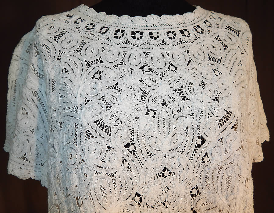 Vintage White Battenburg Tape Lace Sheer Shirt Blouse
This vintage white Battenburg tape lace sheer shirt blouse dates from the 1940s. It is made of a sheer white filmy linen tape lace, with veined, raised threads flowers, leaves, scrolling designs joined by bobbin made braids and thread bars.