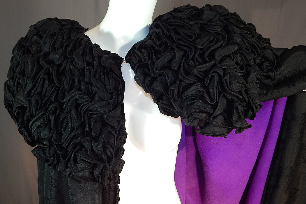 Victorian Black Silk Wool Damask Weave Large Ruffle Collar Cloak Cape
This magnificent mourning cloak cape is a long floor length, with a large ruff shawl collar heavily adorned with gathered ruffles, a hook closure at the neck, ruffle trim edging, a dark purple wool fabric and cotton striped ticking fabric lining inside.