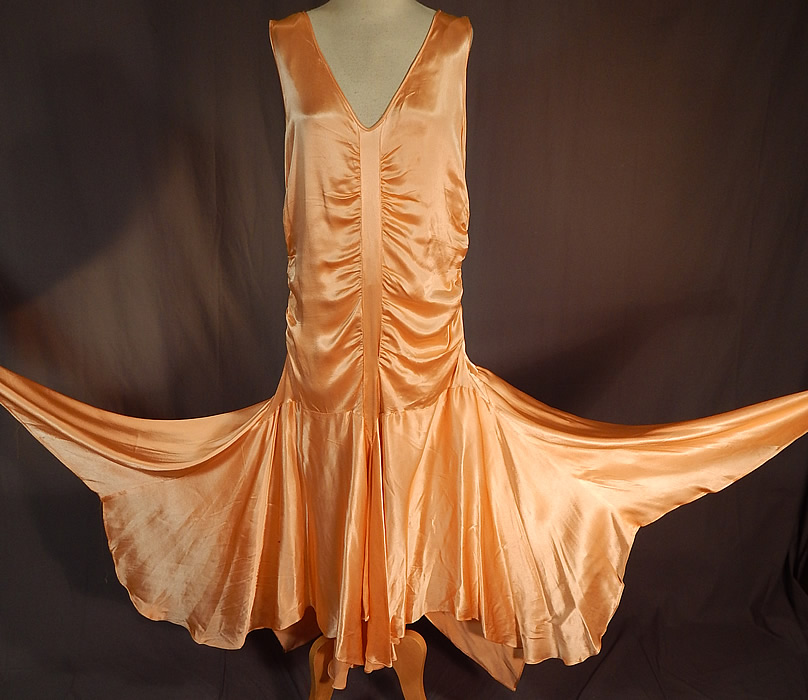 Vintage Peach Silk Satin Charmeuse Handkerchief Hem Skirt Drop Waist Flapper Dress
This vintage peach silk satin charmeuse handkerchief hem skirt drop waist flapper dress dates from the 1920s. It is made of a lustrous pastel peach color silk satin charmeuse fabric, with ruched gathering down the top and sides.