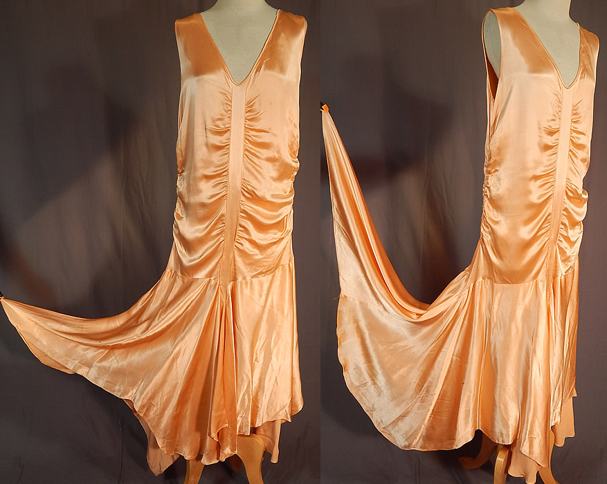 Vintage Peach Silk Satin Charmeuse Handkerchief Hem Skirt Drop Waist Flapper Dress
This fabulous flapper drop waist dress is sleeveless, with plunging V necklines, ruched gathering going down the front, back and sides, an uneven asymmetrical handkerchief hemline full skirt, longer along the sides, side snap closures and has a net lined camisole top.