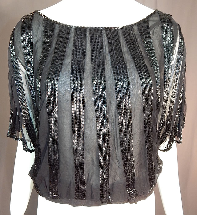 Vintage Art Deco Sheer Black Silk Beaded Batwing Sleeve Blouse Shirt Top
This vintage Art Deco sheer black silk beaded batwing sleeve blouse shirt top dates from the 1920s. It is made of a black sheer mesh fine net silk fabric with black beading done in a striped pattern design.