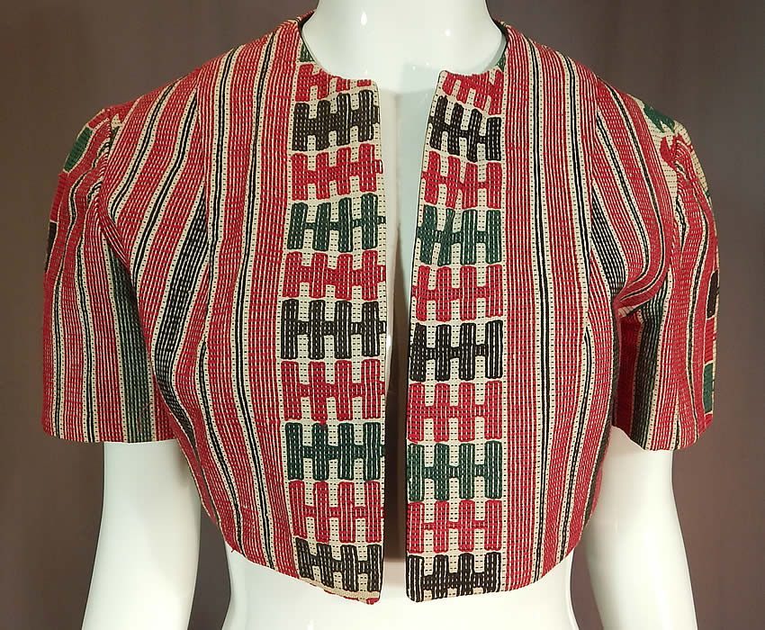 Vintage Ethnic Embroidered Woven Red Short Cropped Boho Bolero Jacket Shrug
This vintage ethnic embroidered woven red short cropped boho bolero jacket shrug dates from the 1940s. It is made of a red, green, black and white woven embroidered cotton fabric with ethnic inspired designs, striped, checkered patterns.