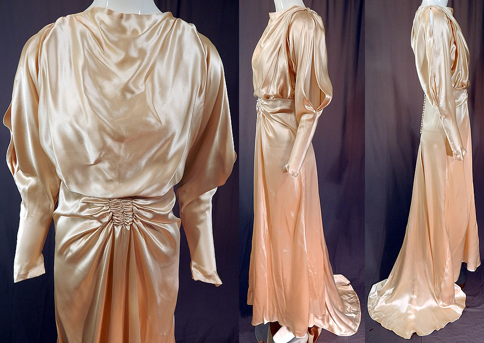 Vintage Cream Silk Charmeuse Cutout Sleeve Bias Cut Wedding Gown Train Dress
This beautiful bridal bias cut long floor length wedding gown dress has ruched gathering on the front waist, shoulders, a draping high neckline, long tapered sleeves with cutout openings on the arm, fitted cuffs coming to a point, a draped back train skirt, silk covered buttons on the bottom back with snaps on the top for closure and has a sheer net camisole lining the top only. 