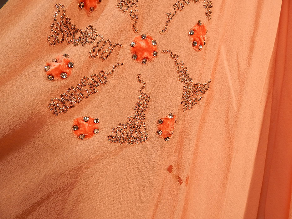 Vintage Art Deco Orange Silk Velvet Applique Rhinestone Beaded Flapper Dress
This fabulous flapper dress has a loose fitting drop waist, sleeveless style, with a wide orange velvet fabric panel draped around the waist, a side sash chiffon tie, full short skirt and is fully lined. The dress measures 44 inches long, with a 38 inch bust and 36 inch waist. 
