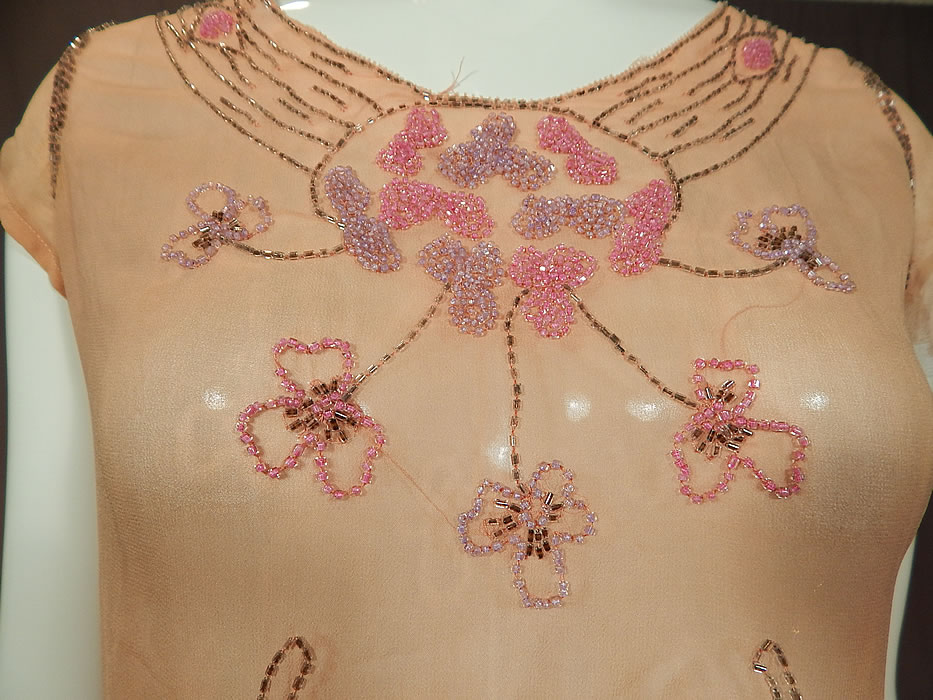 Vintage Art Deco Pink Silk Chiffon Lavender Floral Leaf Beaded Flapper Dress

This fabulous flapper dress has a fitted top, short cap sleeves, scalloped trimmed fitted waist, short full skirt, side snap closures and is sheer, unlined. 