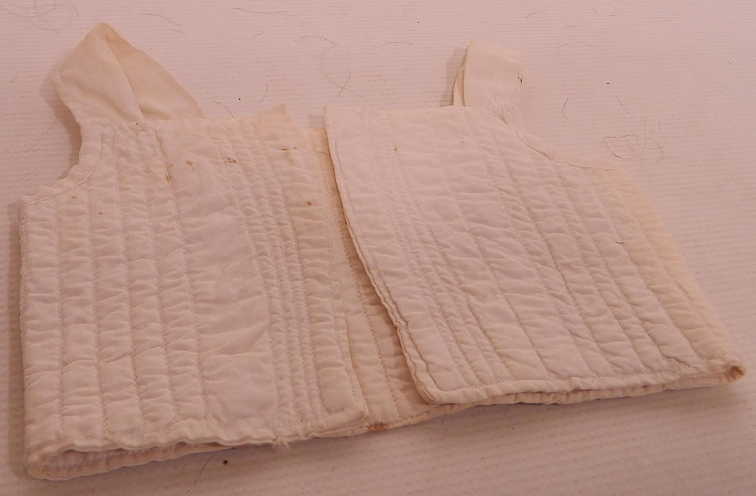 Victorian Antique Doll Infant Child Corset Stays Cotton Quilted Undergarment. The top measures 7 inches long and 16 inches in circumference. It is in good condition, has not been cleaned, with only a few faint tiny age spot stains and slight fraying along the bottom hem and back shoulder strap. This is truly a rare and early piece of antique doll and or children's clothing!